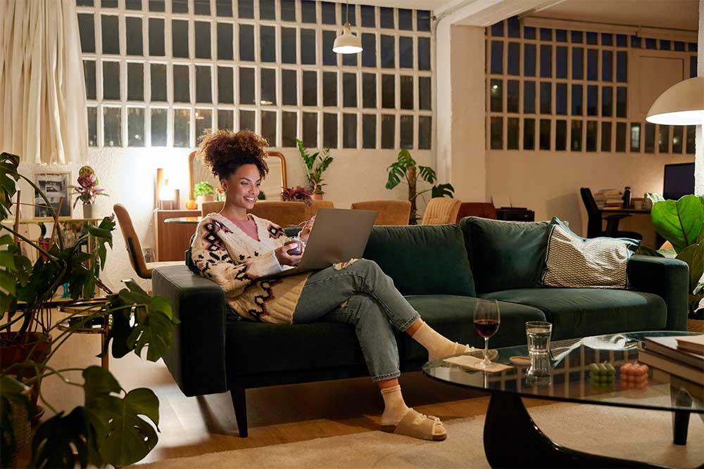 En kvinna som sitter i soffan och kollar på datorn