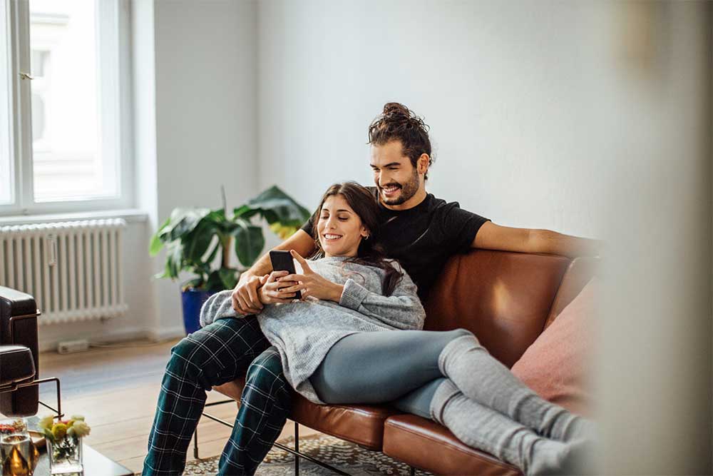 Ett par som sitter i soffan och kollar på bostadsannonser